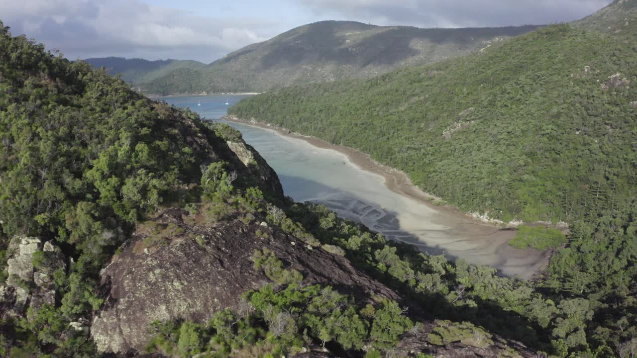 escarpa de roca de sobrevuelo aéreo a la entrada del océano poco profundo y veleros