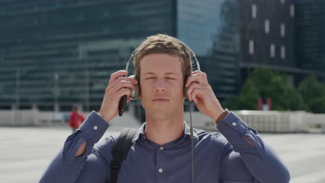 retrato joven atractivo se pone auriculares escuchando música en la ciudad disfrutando de un estilo de vida urbano relajado en un día soleado en cámara lenta