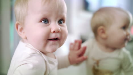 bebé con ojos azules mirando a su madre y mordiendo su dedo. linda niña