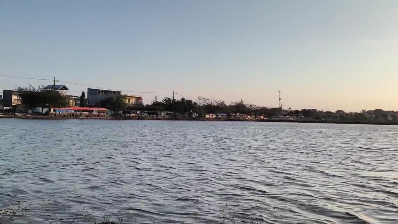 Kräuselndes Seewasser bei Sonnenuntergang in der Nähe von Küstengebäuden