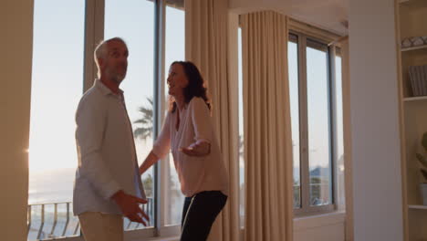 pareja feliz abrazada en una habitación de hotel mirando por la ventana al atardecer disfrutando de un exitoso estilo de vida de jubilación en vacaciones compartiendo una conexión romántica