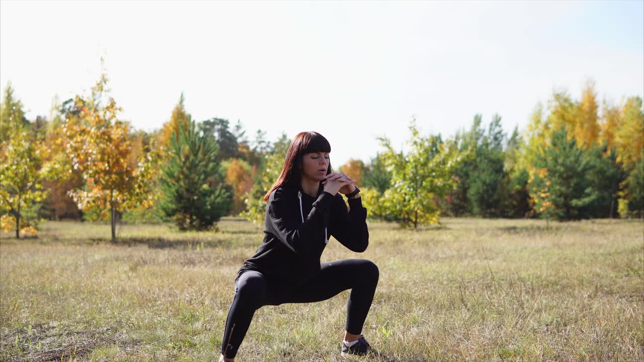 Donna che fa squat in una foresta autunnale