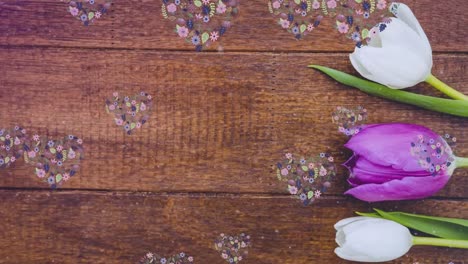 Animation-of-flower-hearts-moving-over-tulips-on-wooden-background