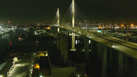 aerial flyby of lit bridge in long beach california | ship sailing underneath | night time