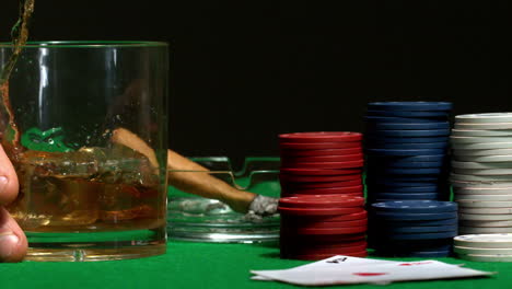 Mano-Poniendo-Un-Vaso-De-Whisky-Sobre-La-Mesa-Del-Casino