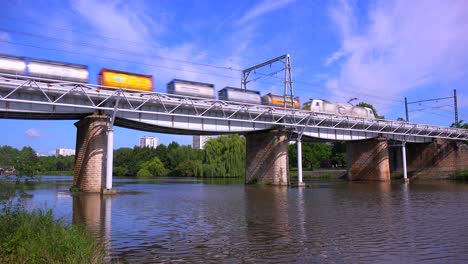 A freight train speeds across a bridge in Europe
