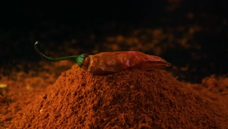 red chilli pepper falling on cayenne pepper powder, slow motion