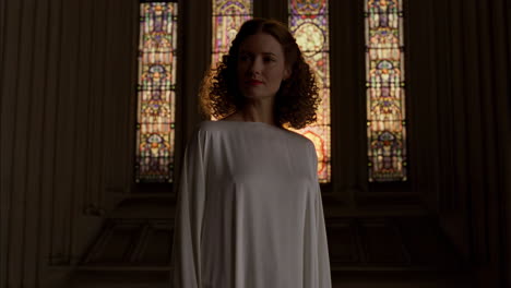 woman in white dress before stained glass windows