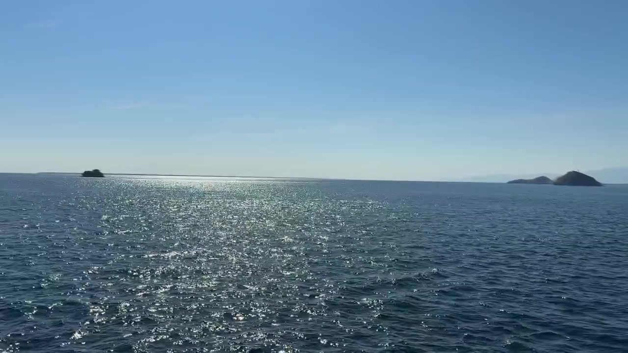 広大な青い海にきらめく陽光と遠くの島々