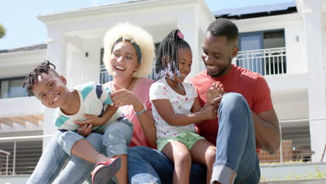 african american man, young biracial woman, and two children smile together