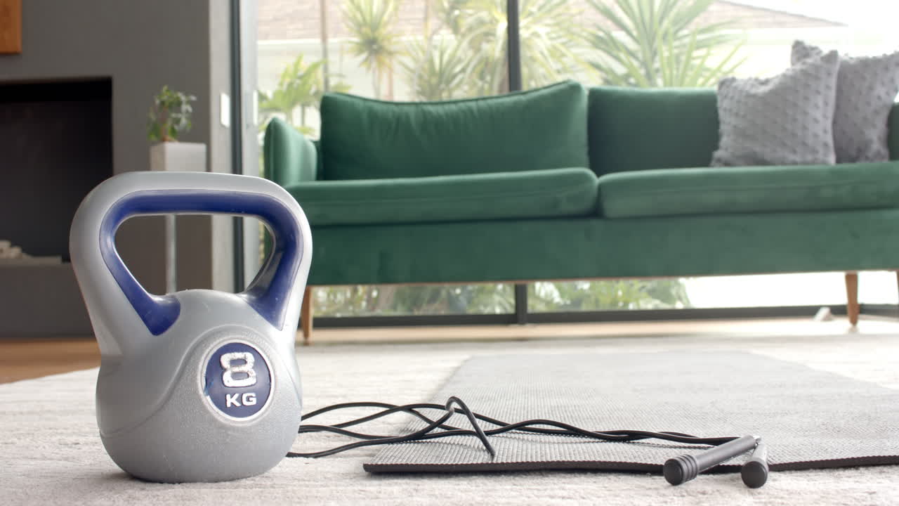 Kettlebell and jump rope on yoga mat in living room, ready for workout, copy space