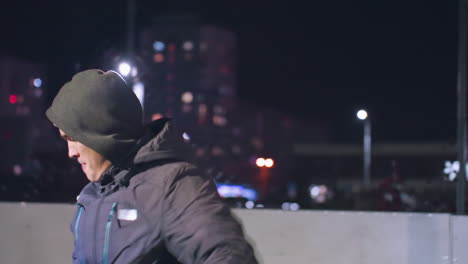 athlete in hoodie and beanie bounces soccer ball once before kicking it with precision during training session under illuminated urban backdrop