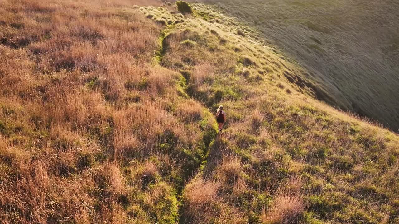 Persona che cammina su un sentiero erboso in collina.