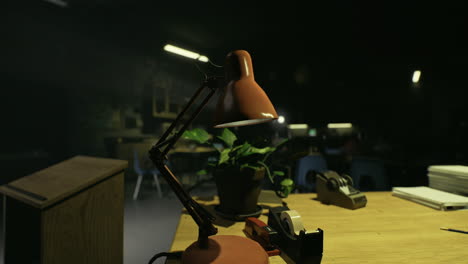 desk with lamp and plant in dimly lit classroom during evening hours