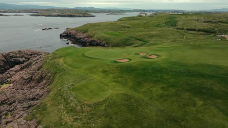 drone flies over cliffside putting green on iconic ireland links golf course along coastline