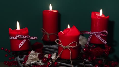 modern christmas wreath with four red candles on wooden surface with green background, holiday interior design