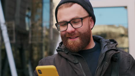 happy bearded man using smartphone in urban setting