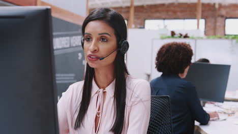 female customer services agent working at desk in call center