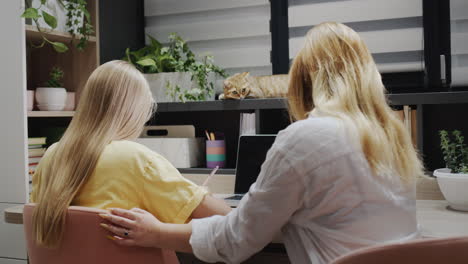 Teacher-or-parent-helping-a-girl-who-is-working-with-a-laptop-in-the-classroom