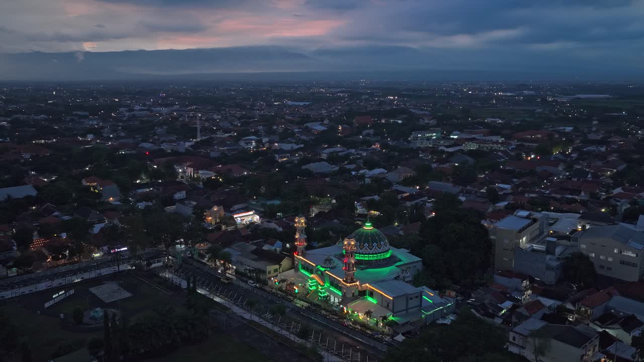 Perspektif udara yang menakjubkan dari kota Probolinggo di Jawa Timur, Indonesia, menampilkan sebuah masjid agung yang diterangi cahaya hijau terang saat senja