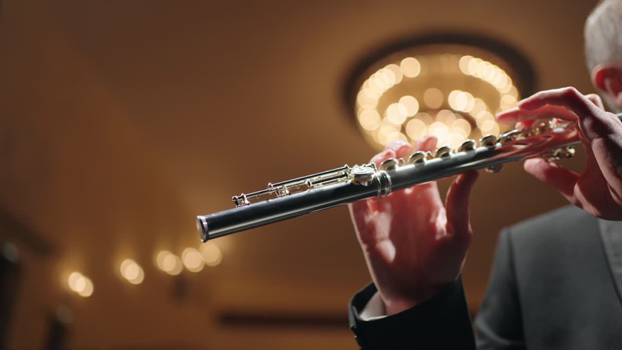 필하모닉 홀 의 청동기 오케스트라 플루트 연주자 가 플루트 를 연주 하고 있다