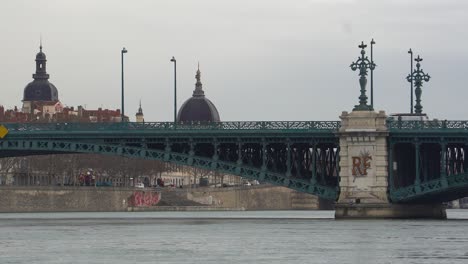 Buses-and-Pedestrians-Cross-Lyon's-Old-Iron-University-Bridge,-Adorned-with-Arches-and-Decorative-Wrought-Iron-Stanchions