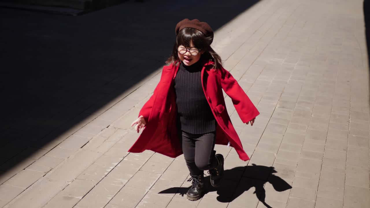 은 코트를 입은 유행하는 한국 아기 소녀가 봄에 거리를 고 있습니다.