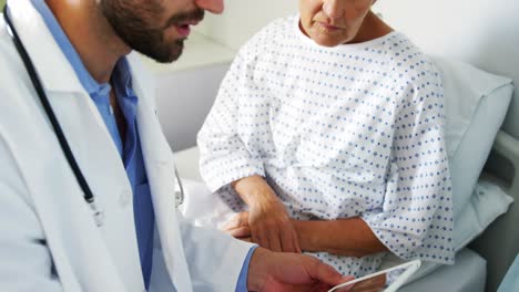 Male-doctor-discussing-medical-report-with-female-patient-on-digital-tablet