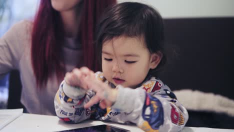 an adorable cute asian toddler boy is playing games on cellphone.