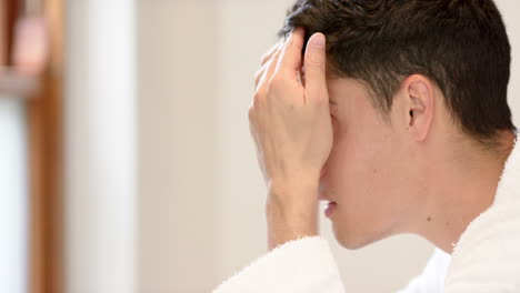 feliz hombre biracial inspeccionando el cabello y la cara en el espejo del baño y sonriendo, copia espacio, cámara lenta