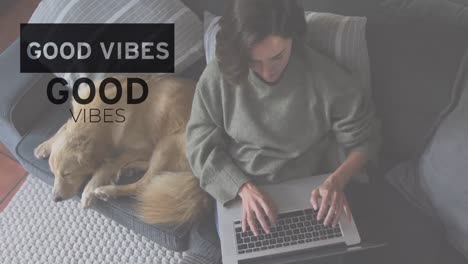 animation of good vibes text over caucasian woman using laptop with dog