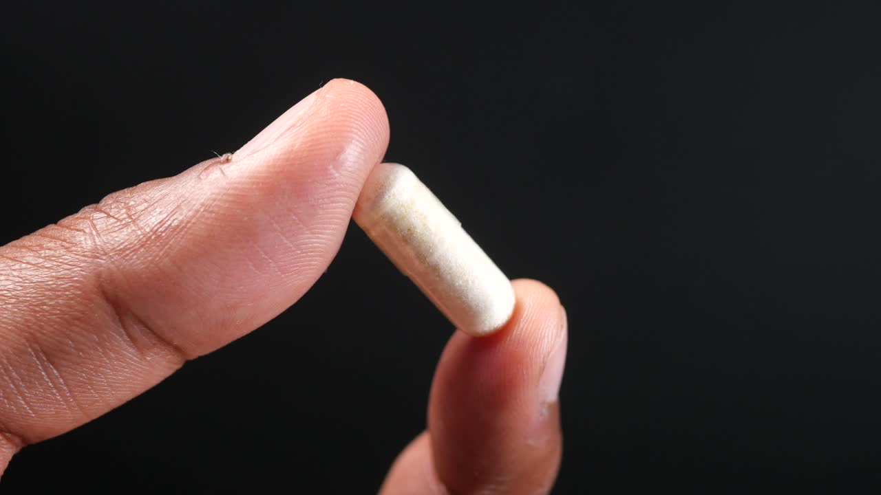 mano con una cápsula blanca de píldora