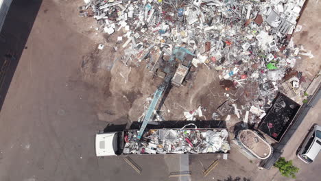 una grúa de basura cargando un camión con escombros de un depósito de chatarra