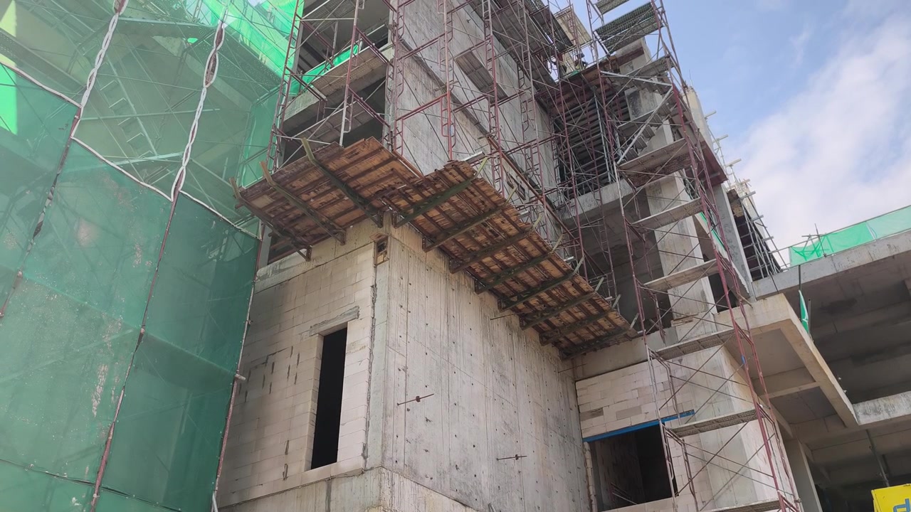 Una piattaforma di lavoro a sbalzo sostenuta da staffe per ponteggi su un edificio. Contiene impalcature aggiuntive utilizzate per la costruzione di muri esterni.