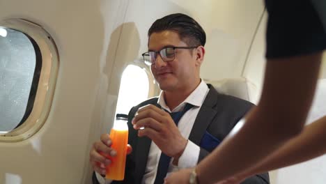 businessman have orange juice served by an air hostess in airplane