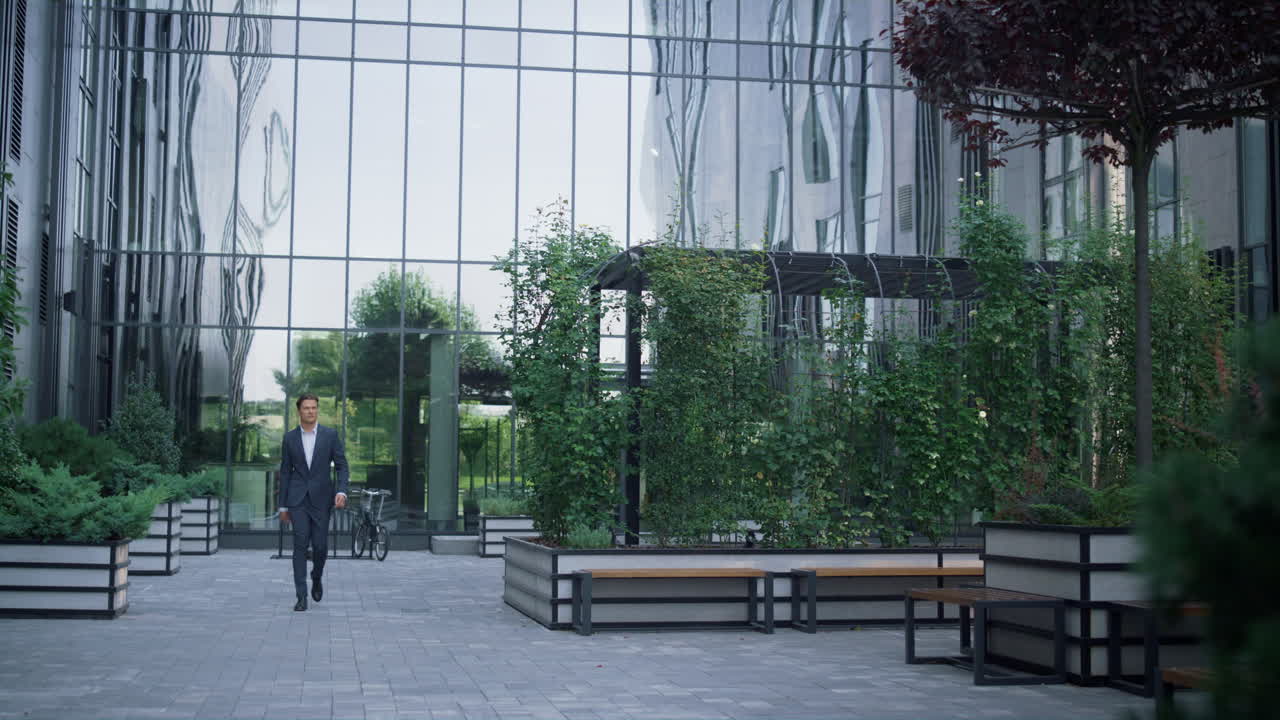 Confident businessman walking business center garden alone. Recreation place.