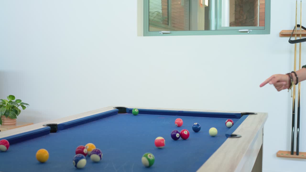 African American man aiming cue then breaking balls on home pool table for fun copy space