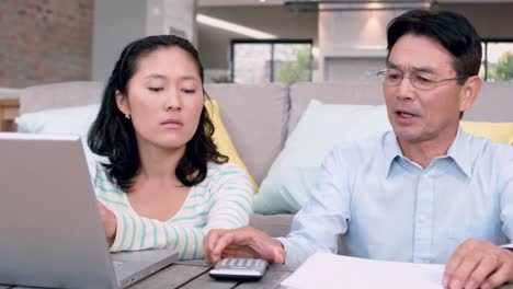 concetrated couple calculating bills with laptop