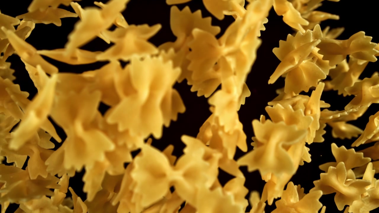 Pasta farfalle cruda sospesa in aria su sfondo nero