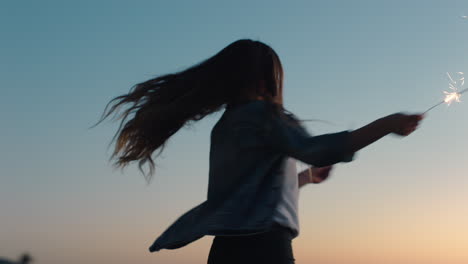 Adolescente-Bailando-Con-Bengalas-En-La-Playa-Al-Atardecer-Celebrando-La-Víspera-De-Año-Nuevo-Divirtiéndose-Celebración-Del-Día-De-La-Independencia-Con-Fuegos-Artificiales-Disfrutando-De-La-Libertad