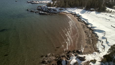 Drone-flight-over-the-ocean-in-winter-with-snow-in-Chandler,-Quebec,-Canada