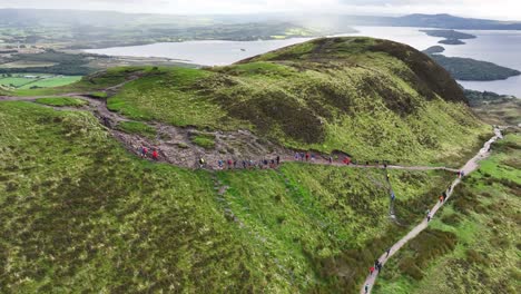 Bergwanderer,-Die-Auf-Den-Gipfel-Des-Konischen-Hügels-Klettern,-Mit-Loch-Lomond-Im-Hintergrund