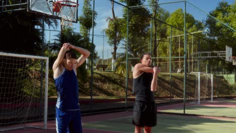 two male athletes stretching on an outdoor sports court