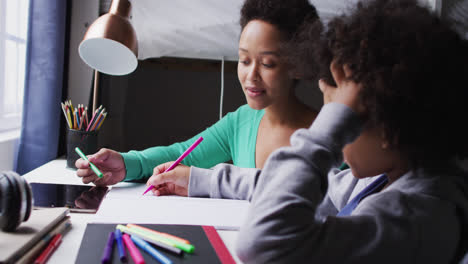 Mixed-race-mother-and-daughter-drawing-in-a-notebook