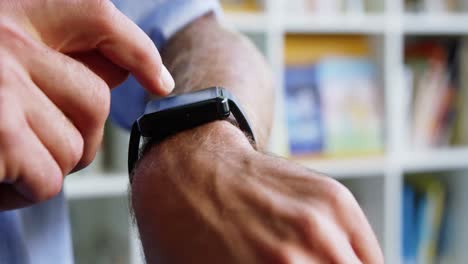 Close-up-of-teacher-adjusting-a-smart-watch-in-library-at-school