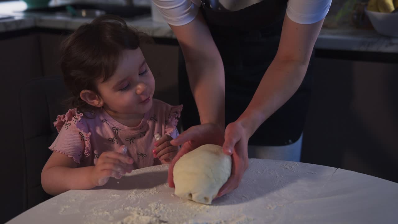 Young Girl Learning to Knead Dough with Adult in Kitchen