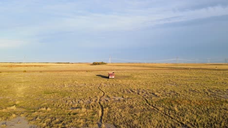 Camión-Rojo-Viejo-Y-Antiguo-Estacionado-En-Una-Enorme-Llanura-Seca-Filmado-Al-Atardecer-Mientras-Un-Pájaro-Vuela-Alrededor