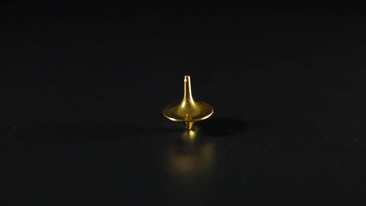 Golden top spinning on a black surface