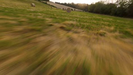 flying leftwards in a hay bales field with an fpv drone at sunset