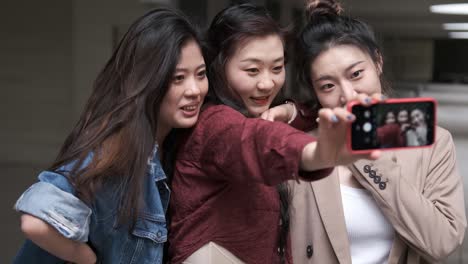 portrait of a group of asian women friends taking a selfie with a mobile phone together.